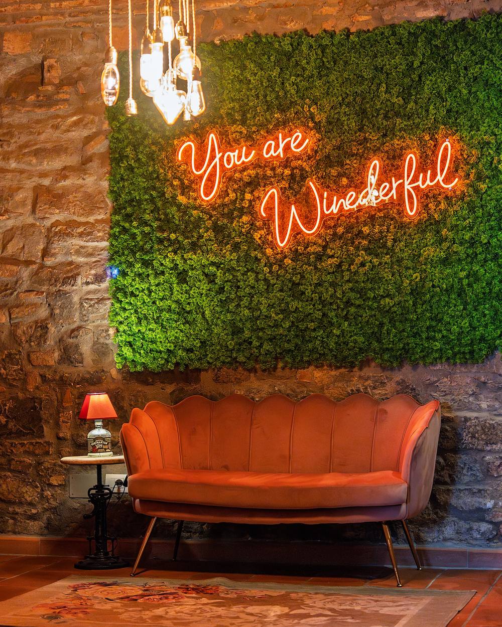 L'angolo lounge: parete di muschio con il neon «You are Winederful», divano a conchiglia rosa e lampadine a filamento