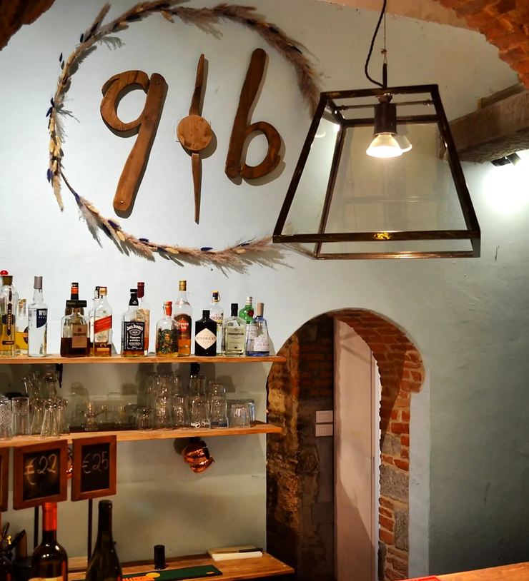 Il marchio q·b intagliato nel legno, montato sopra il bancone del bar