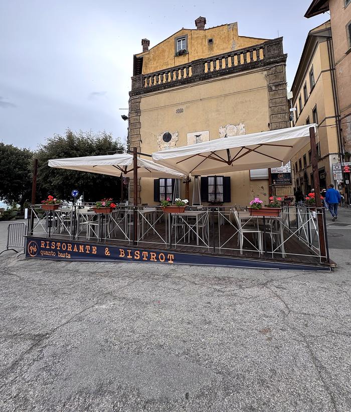 La terrazza di Quanto Basta su Piazza Garibaldi, con gli ombrelloni e la balaustra sulla valle